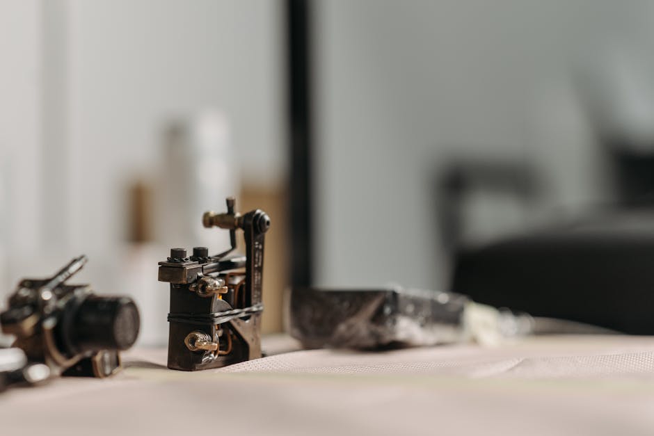 Vari tipi di macchinari per tatuaggio: macchine a bobina, rotative e penne, disposte su un tavolo da lavoro professionale.